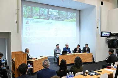 a lecture room with a crowd watching a panel discussion