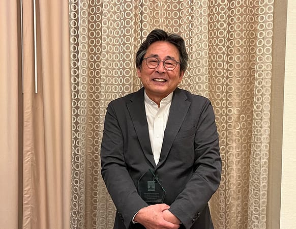 a man in a blazer and white collar shirt holding an award