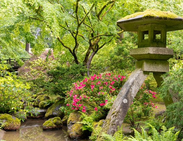 a stone lantern next to pink flowers