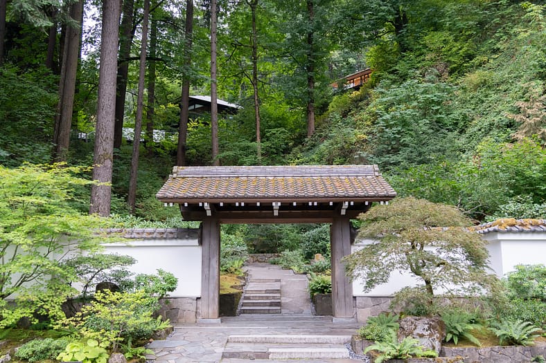 a wooden gate in front of tall trees