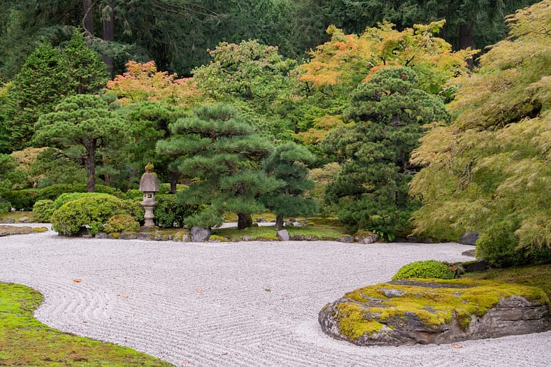 a raked gravel garden with a stone lantern in the background