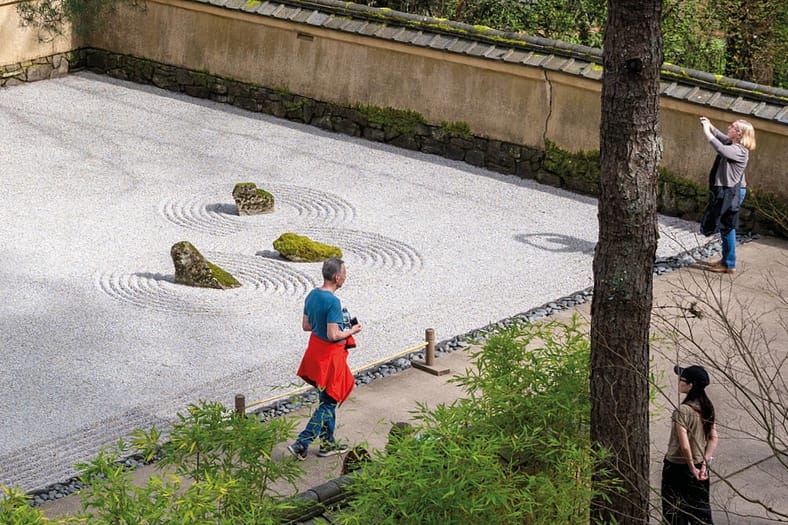 people walking near a raked gravel garden
