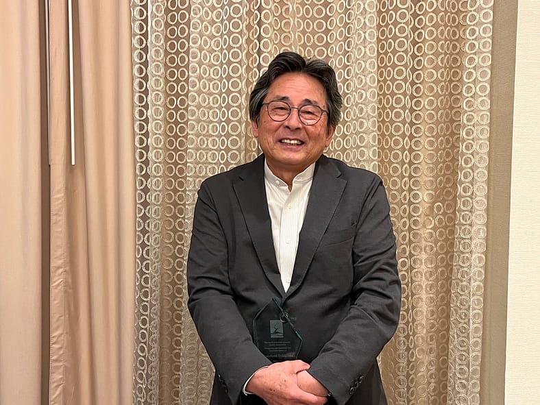 a man in a blazer and white collar shirt holding an award