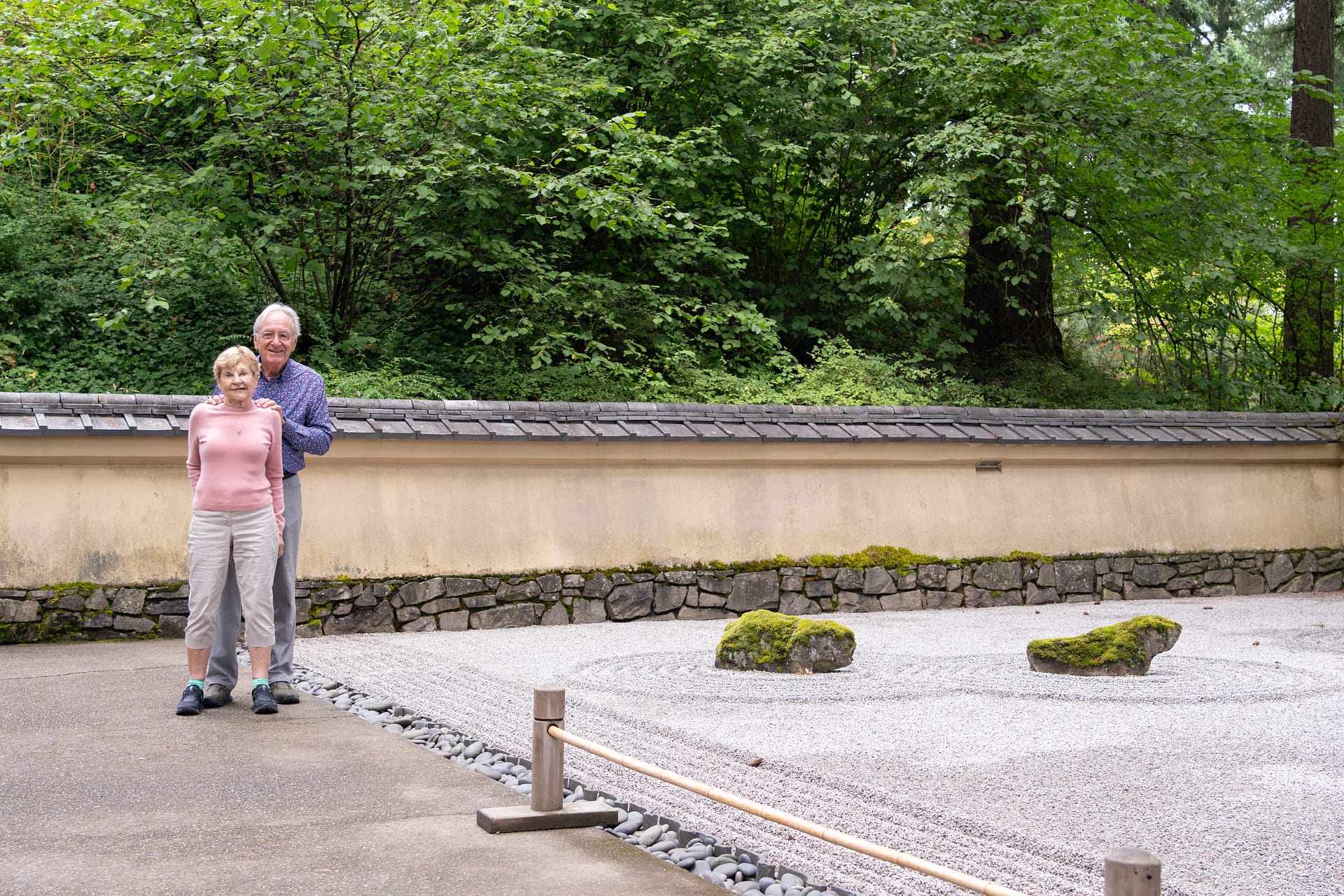two people stand near a raked gravel garden with mossy stones nearby