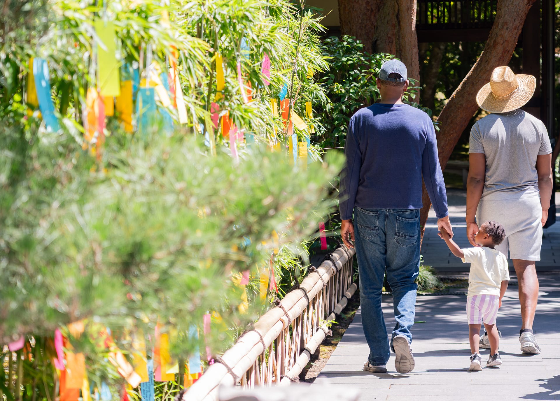 a small child looks at colorful pieces of paper tied to bamboo