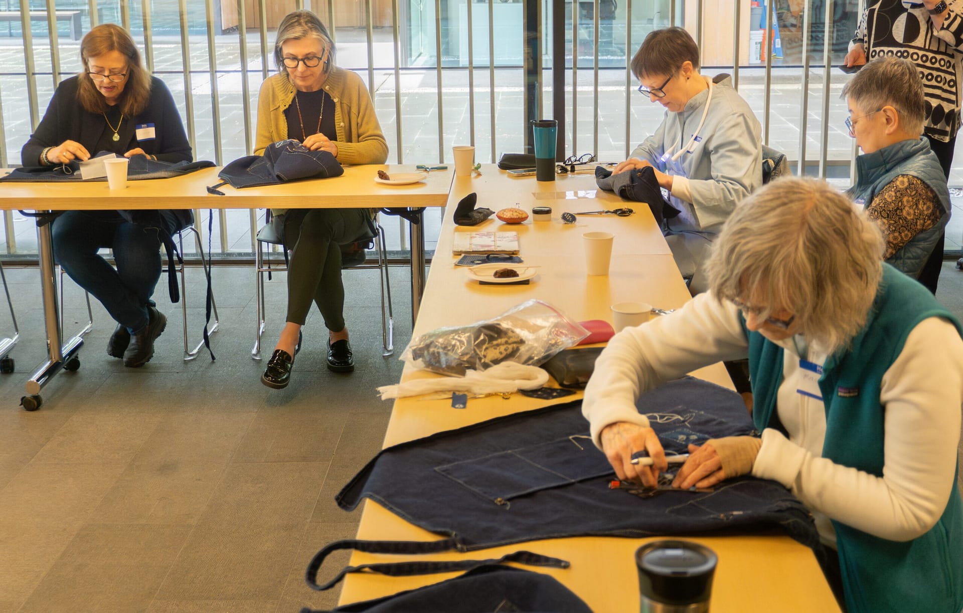 A group of women stitch patterns into denim aprons.