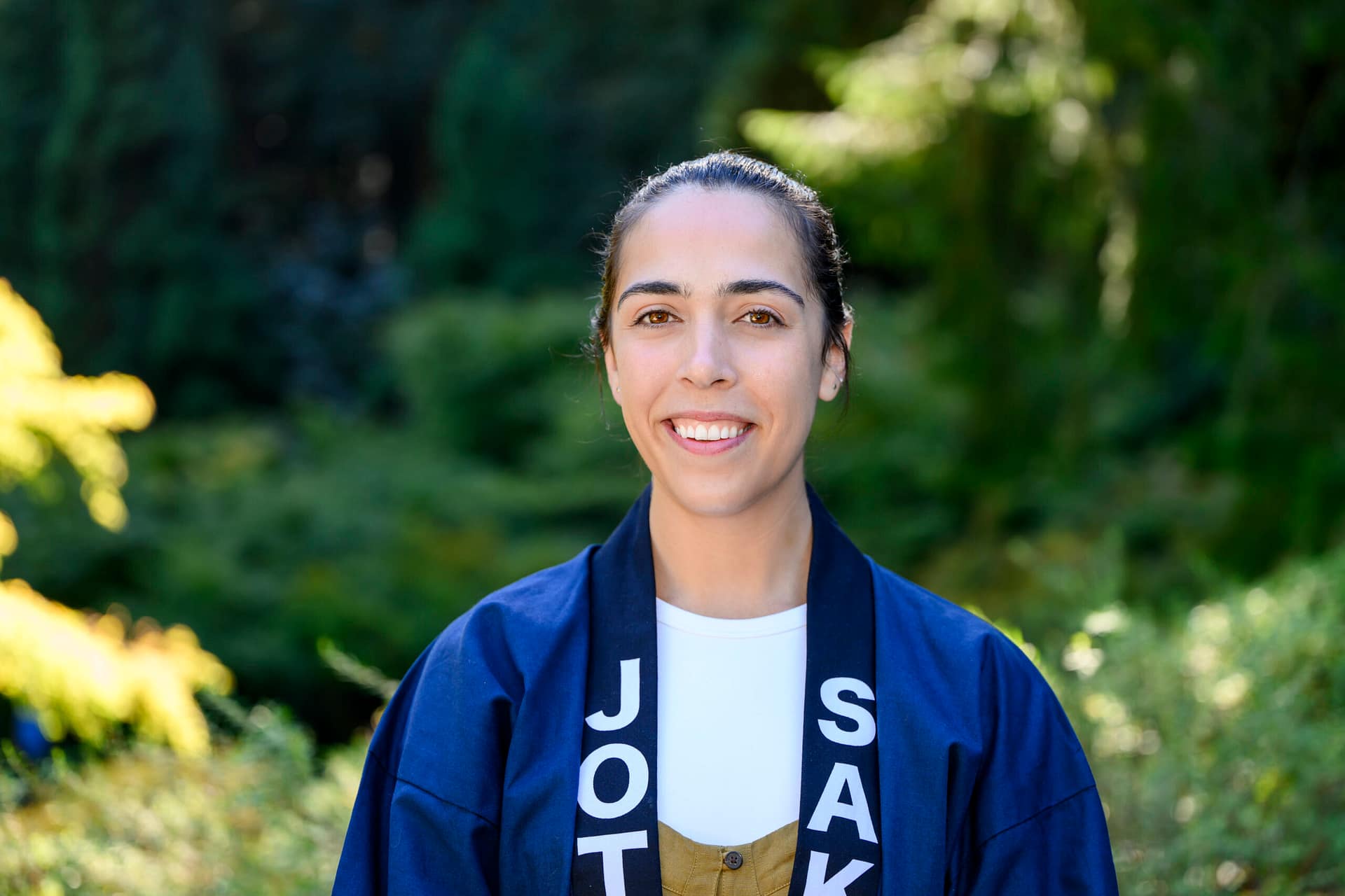 Ryan Mellinger stands wearing a blue jacket that says Joto Sake on it.