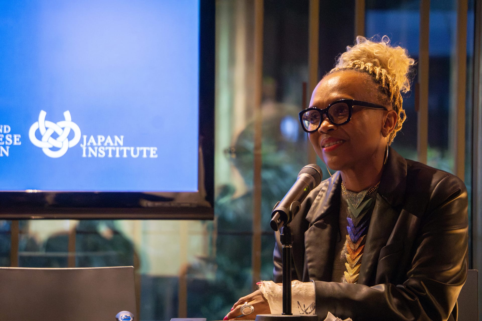 woman sits at table with microphone in front of her