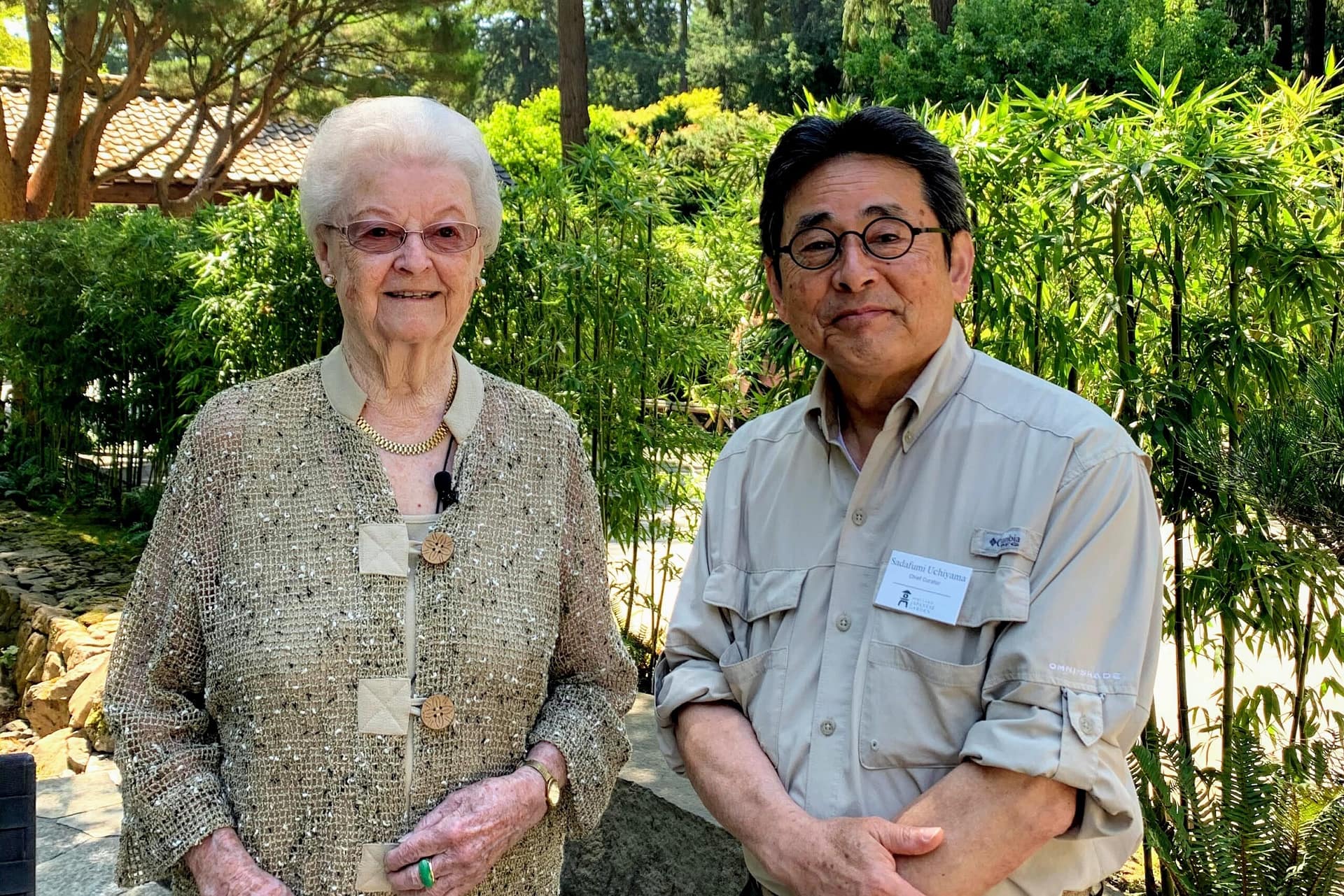 Maggie Drake and Sadafumi Uchiyama standing, posing for a picture within the Portland Japanese Garden.