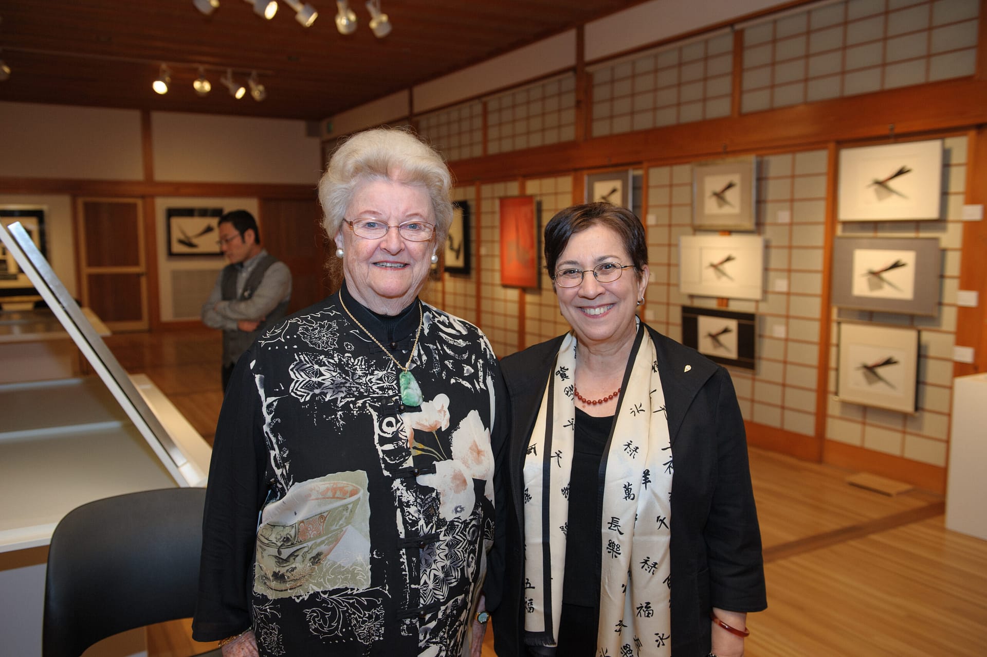 Maggie Drake with Diane Durstan posting in front of art exhibition.