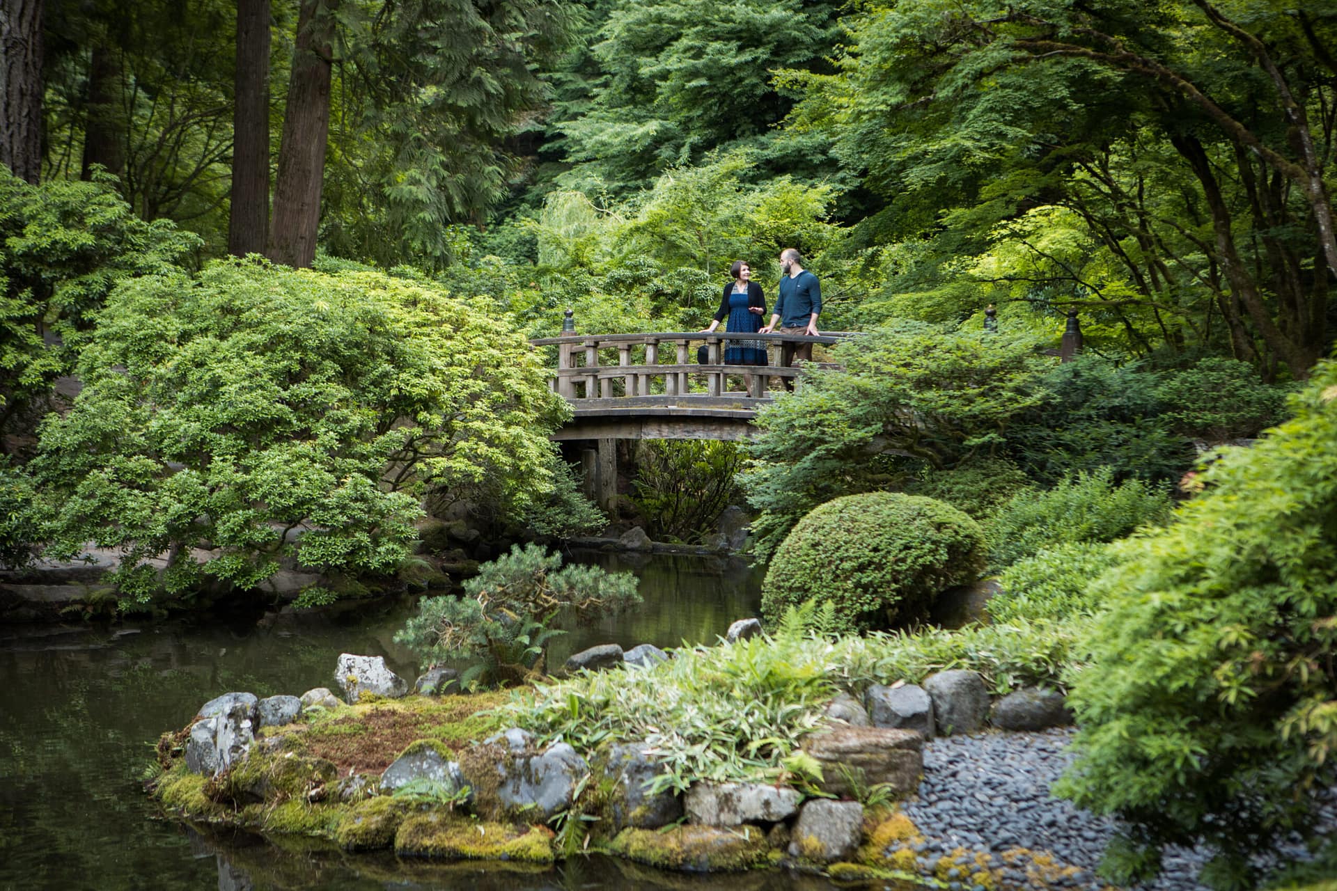 two people standing on a wooden bridge