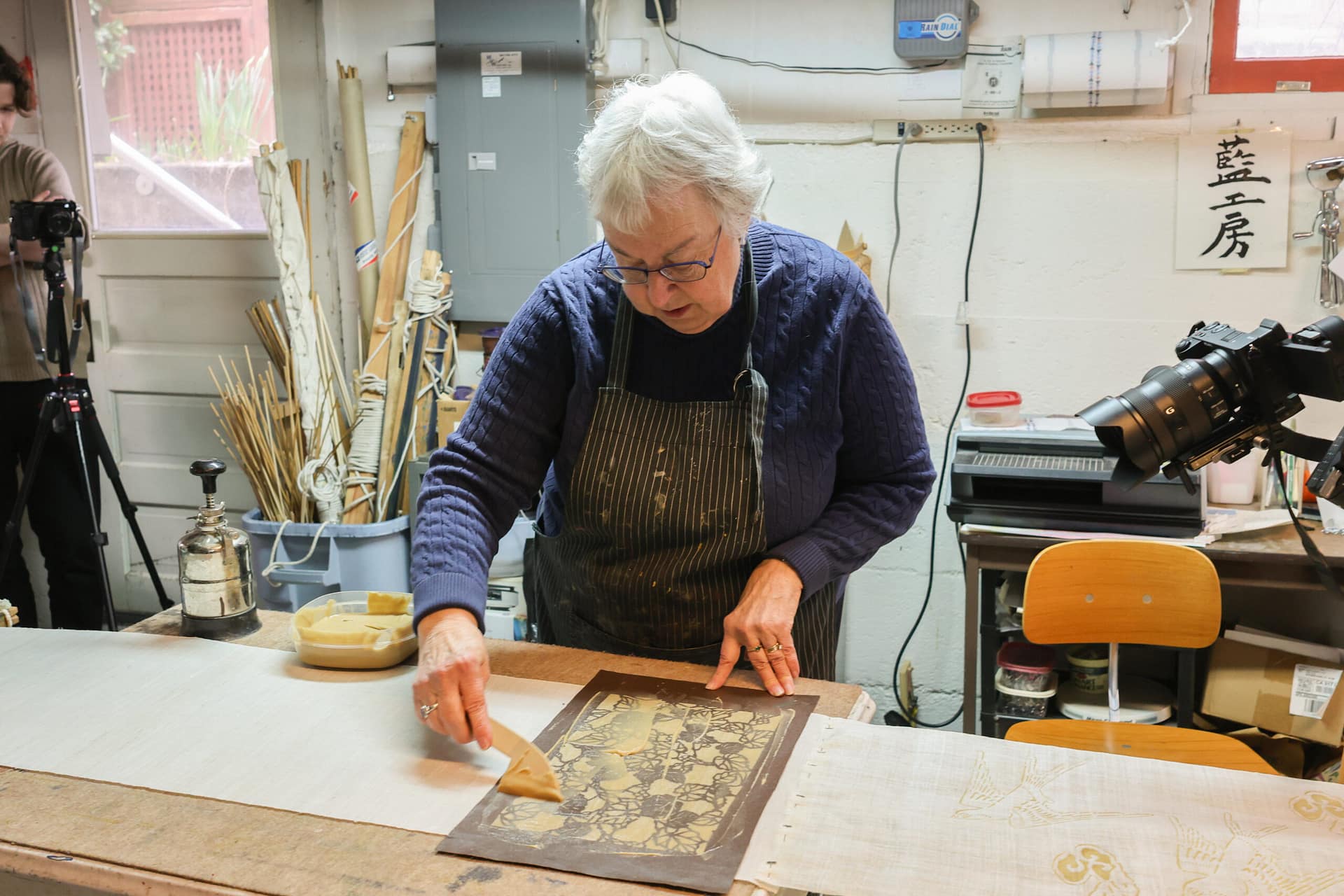 a woman brushing resist paste onto fabric