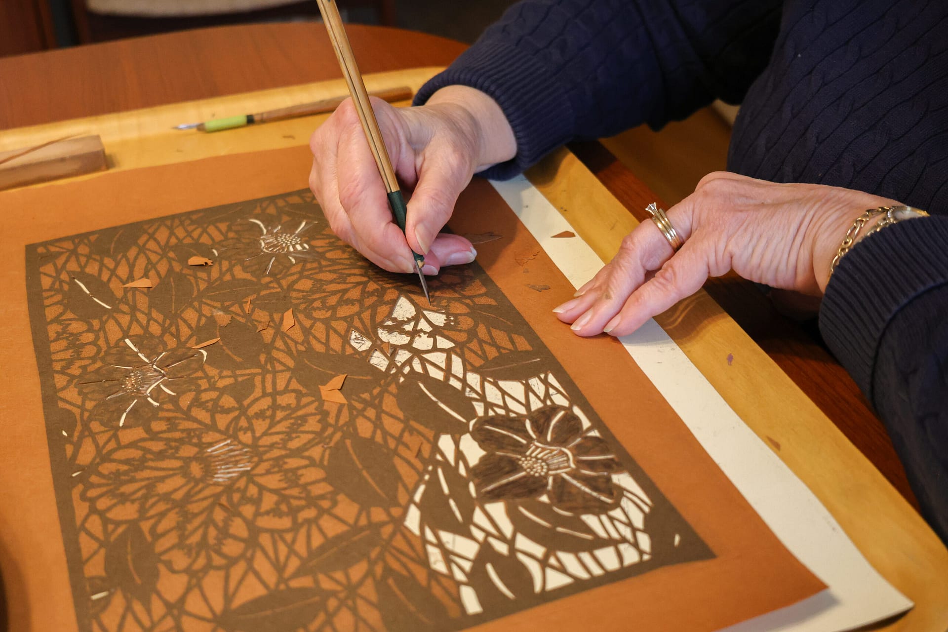 an X-acto knife cuts a pattern into mulberry paper