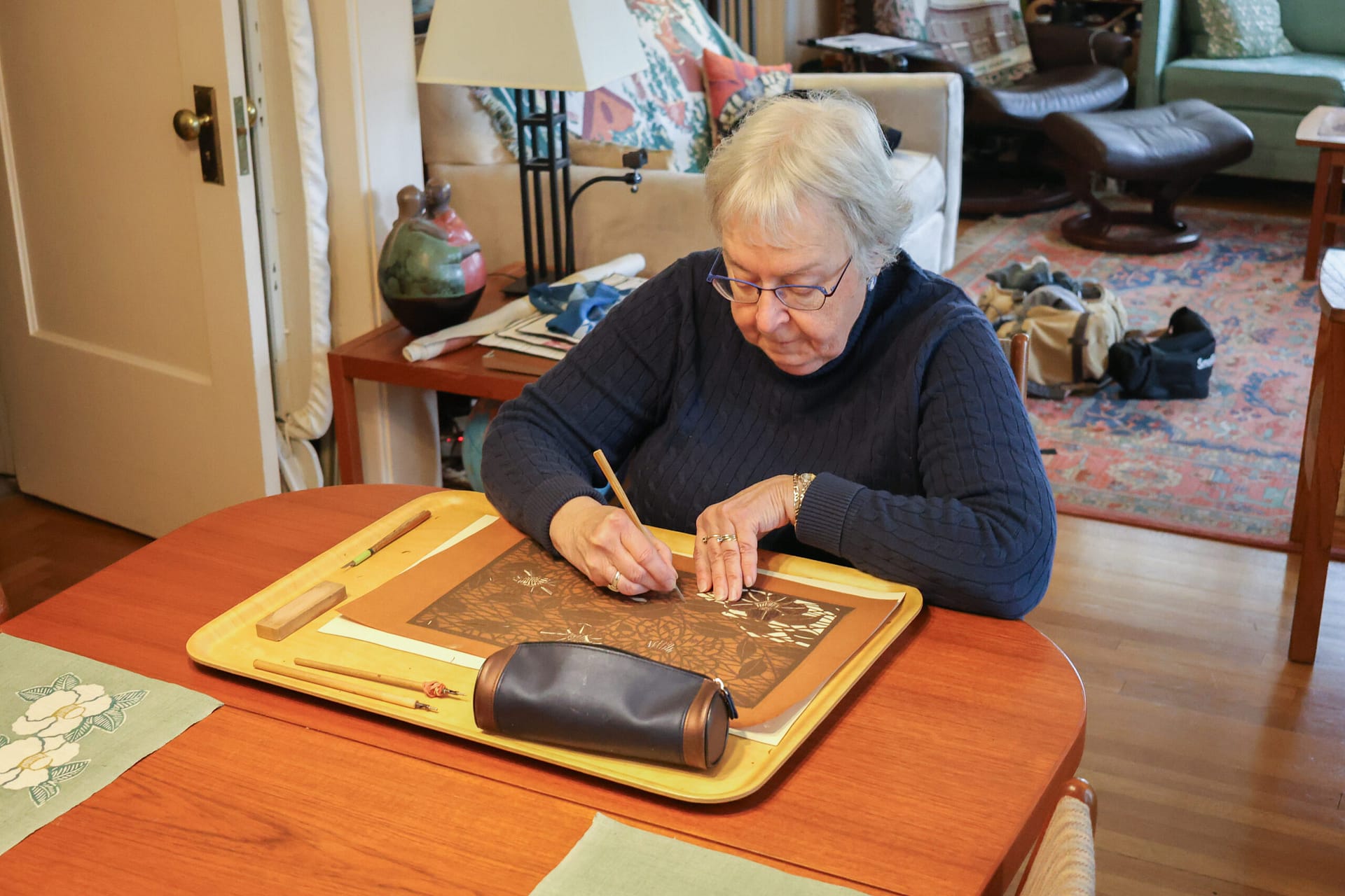 a woman uses an X-acto knife cuts a pattern into mulberry paper
