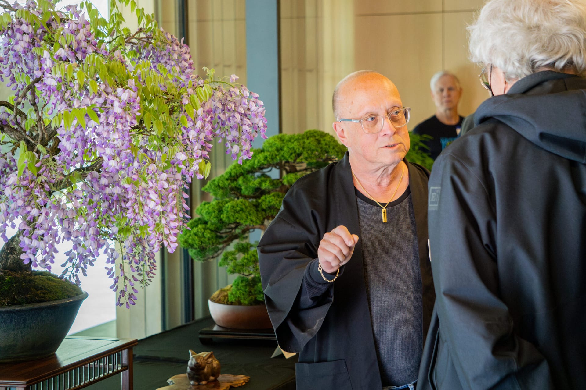 a man stands next bonsai