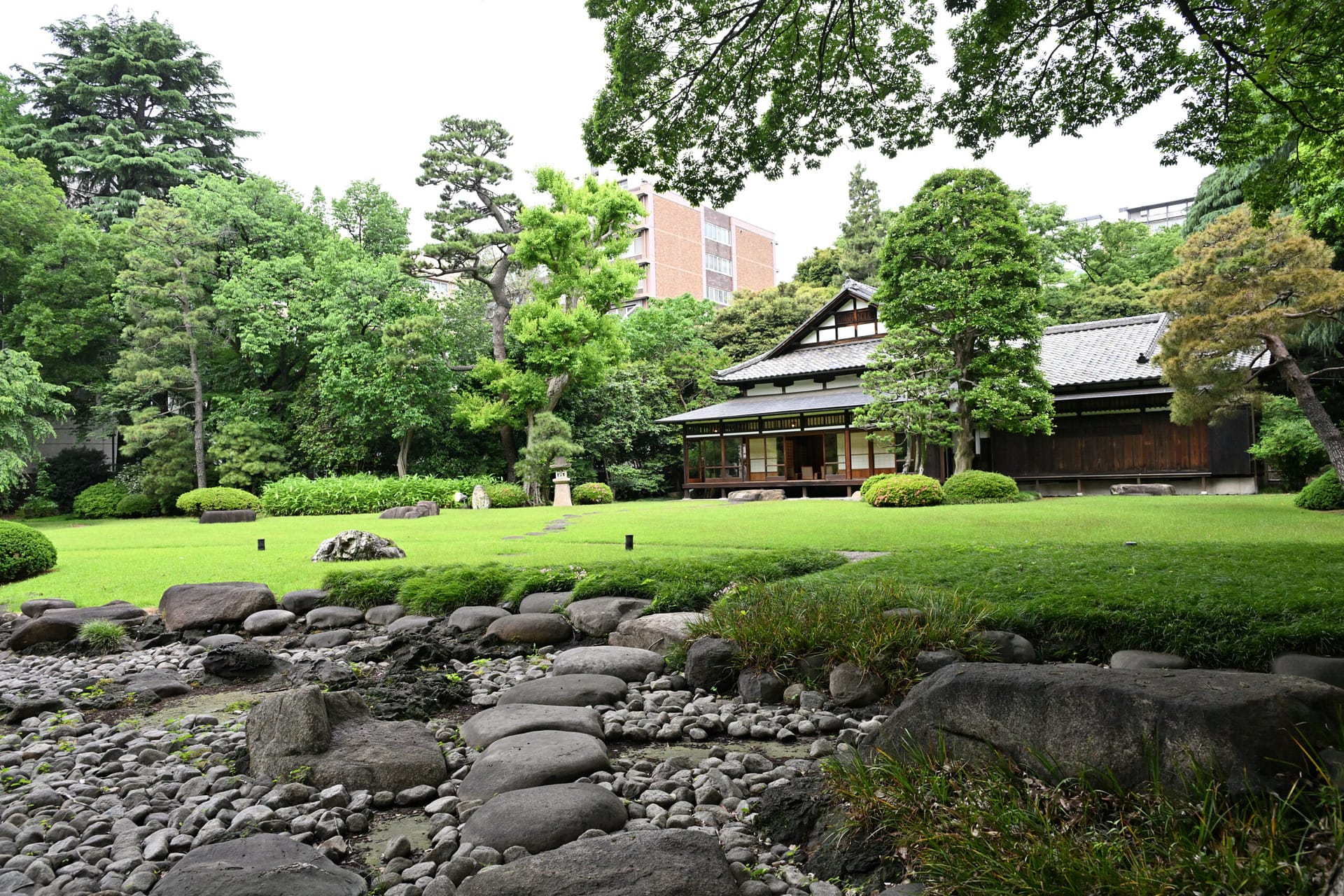 a garden with a building and sweeping lawn in front