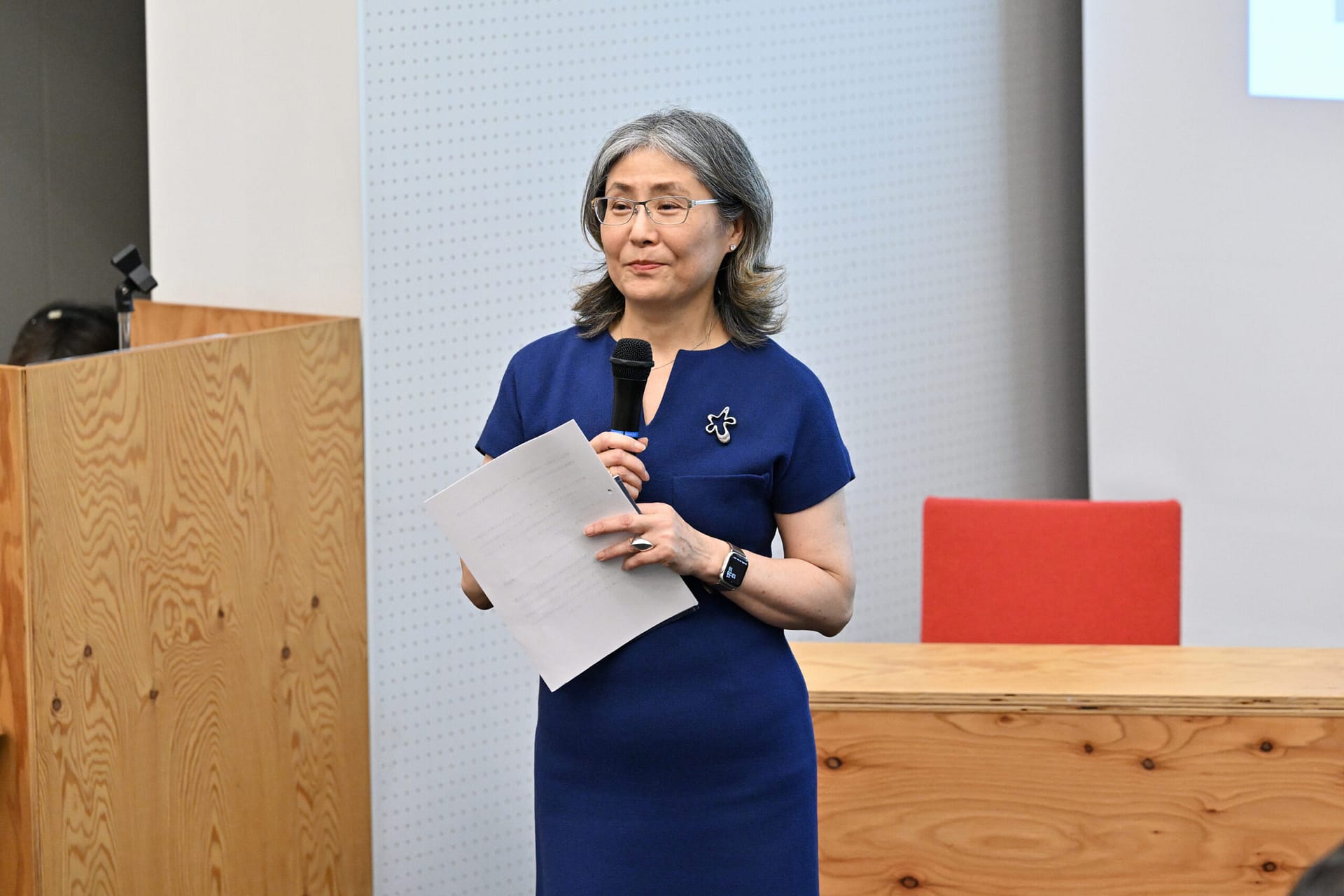 a woman holding a microphone looking at an audience