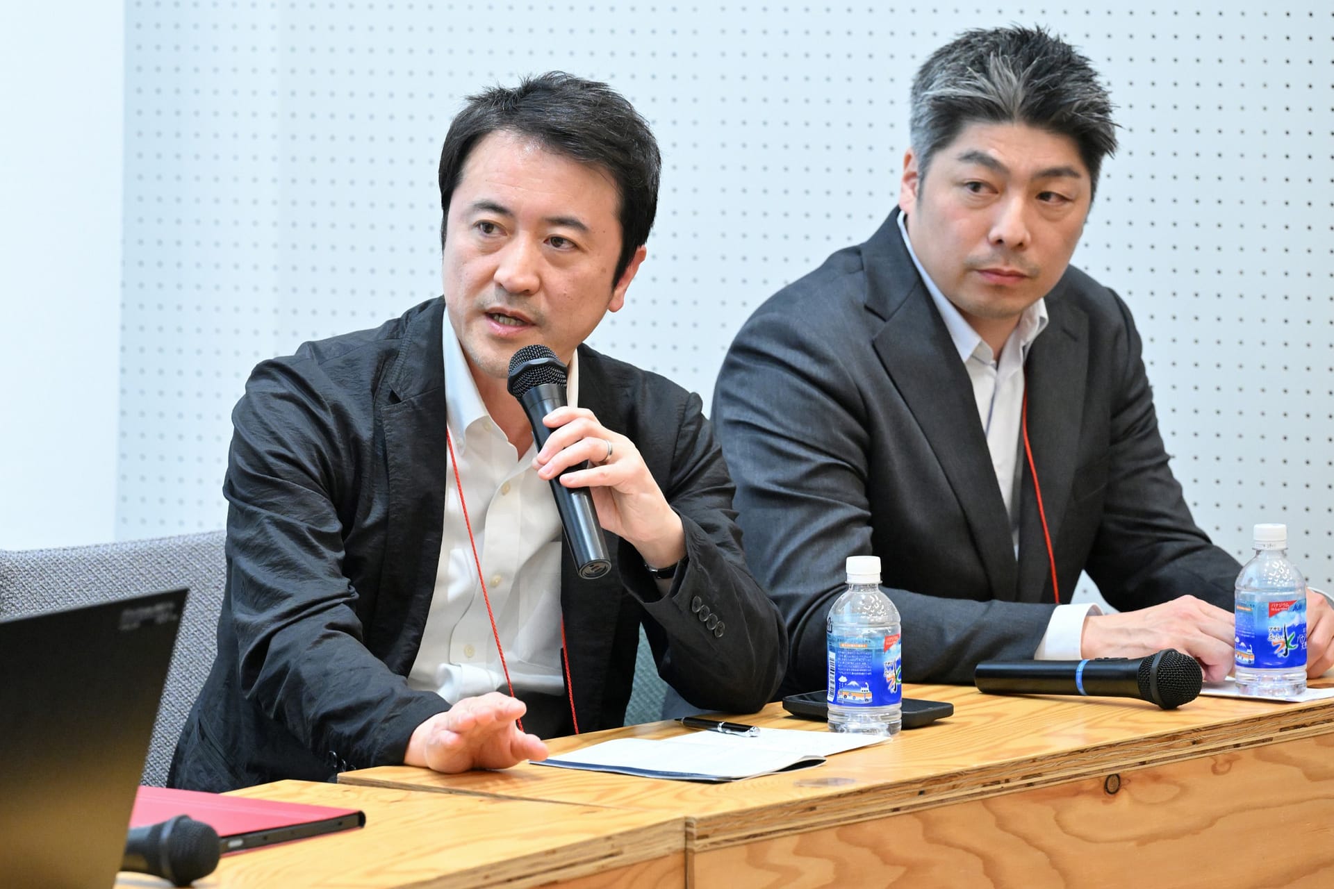 man speaking into a microphone while another listens