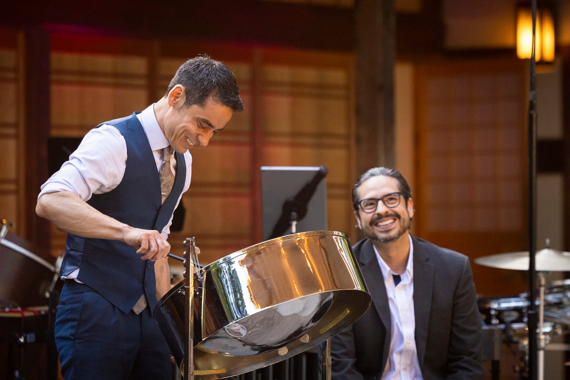 two men smiling while playing steel drum